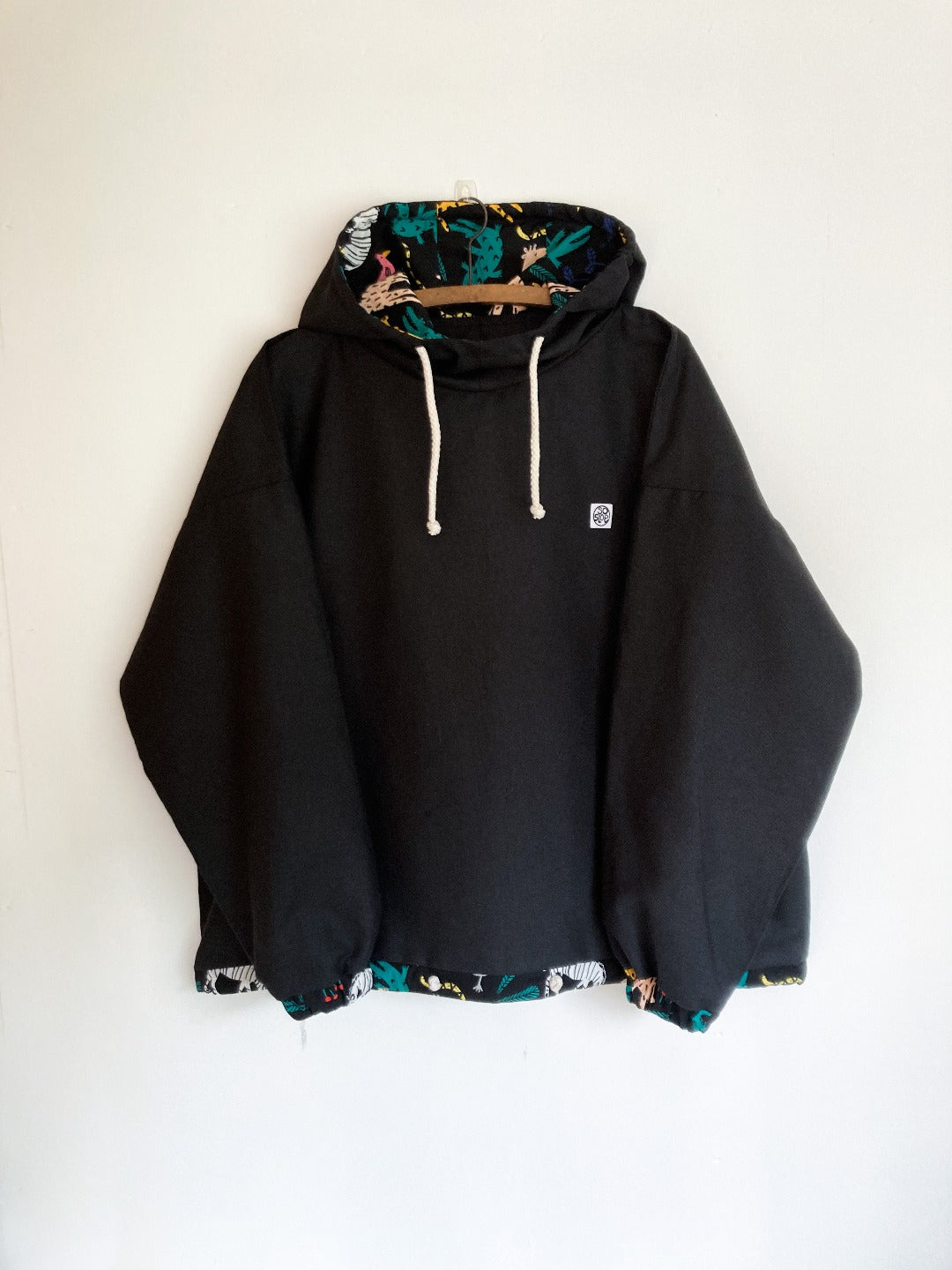Black pullover with jungle print lines hood and cuffs.